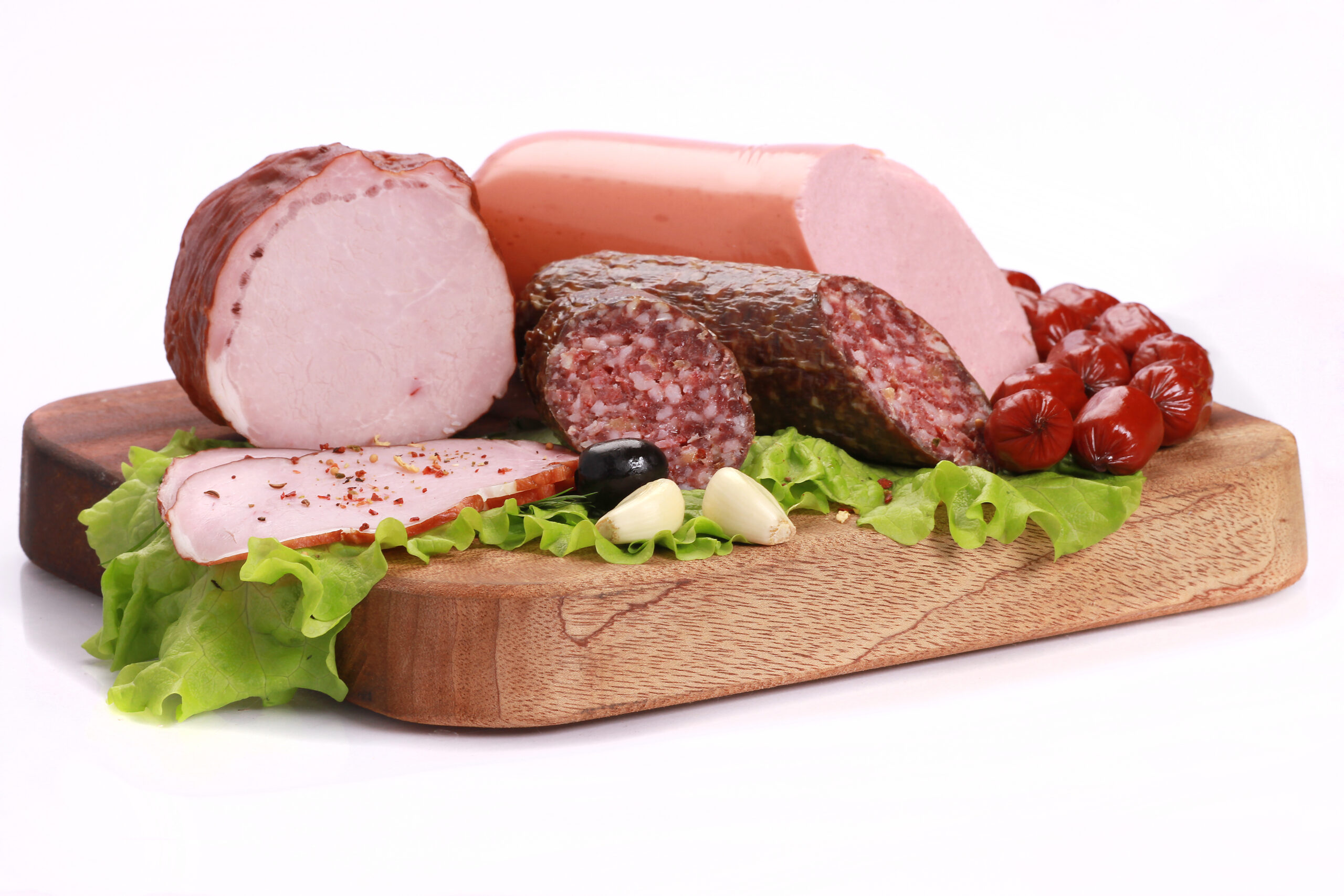 Closeup shot of slices of sausages with green lettuce on a wooden board